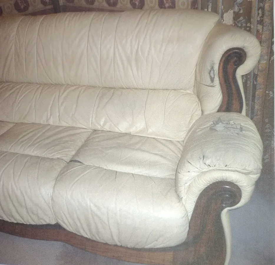 Cream leather suite with a cracked, worn arm and shoulder